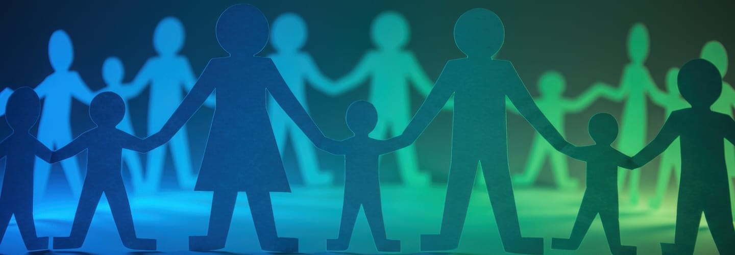 Paper chain of adults and children holding hands. Figures cut from translucent vellum paper illuminated by blue and green light. Family concept, unity.