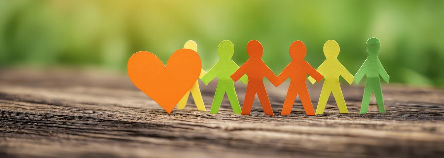 The colorful paper figures representing love and community connection on a wooden surface.